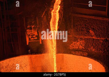 A stream of molten slag is poured into a metallurgical ladle Stock Photo