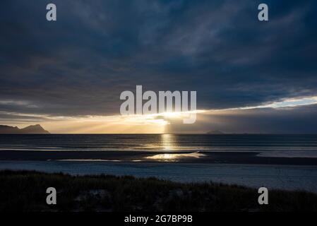 Sun shines through clouds over sea Stock Photo
