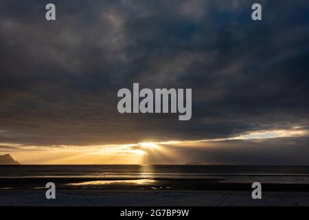 Sun shines through clouds over sea Stock Photo