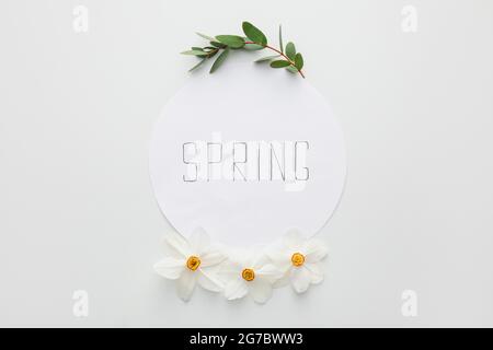 Paper sheet with word SPRING and beautiful daffodils on light background Stock Photo