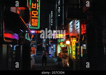 28.04.2013, Seoul, South Korea, Asia - Man is seen standing in a dark alleyway surrounded by colourful neon lights in the popular nightlife district. Stock Photo