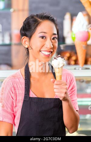 Young Asian saleswoman in an ice cream parlor with ice cream cornet Stock Photo