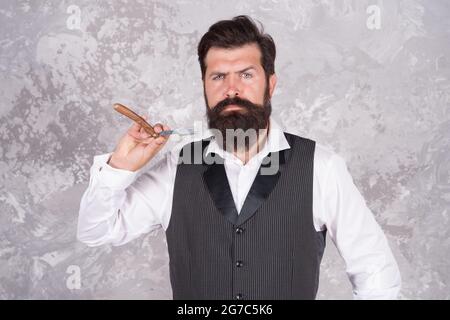 Enjoying morning routine. Master cuts hair and beard in barbershop. hairdresser makes hairstyle. gentleman shaving with retro razor blade. brutal Stock Photo