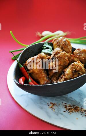 Hot and spicy chicken wings with red chilli on black bowl on red background with copyspace Stock Photo