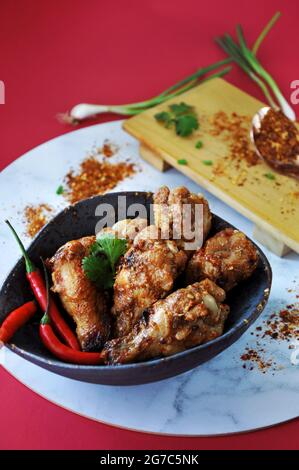 Hot and Spicy chicken wings serving in bowl with red chilli and ingredients on background with space for text Stock Photo