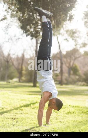 Man doing handstand on grass in the park. Stock Photo