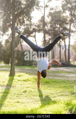 Gymnastic man handstand on one hand doing acrobatic posture Stock Photo