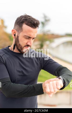 Young runner man with headphones training and checking stopwatch. Stock Photo