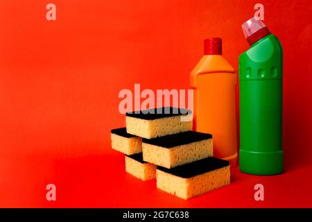 two bottles of cleaning products and cleaning sponges on a red background. Stock Photo