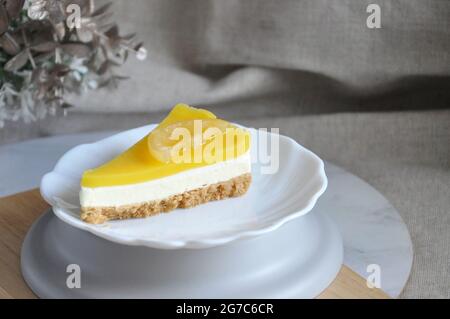 A slice of lemon cheese tart on white dish with copy space on neutral color background Stock Photo