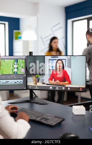 Black woman videographer in web online conference with project manager on video call editing client work, getting feedback on commercial movie using post production software on pc in start up office Stock Photo