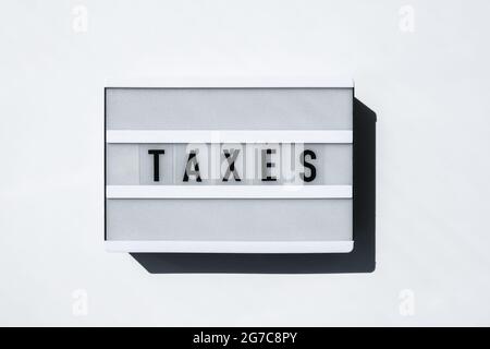 Lightbox board on a white background with the words TAXES in black letters. Currency, cash Stock Photo