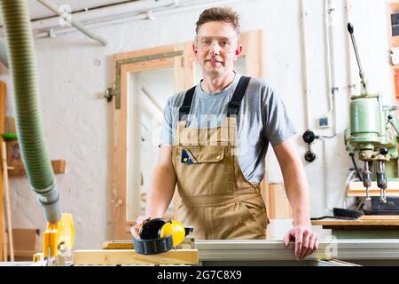 Carpenter working on an electric buzz saw cutting some boards Stock Photo