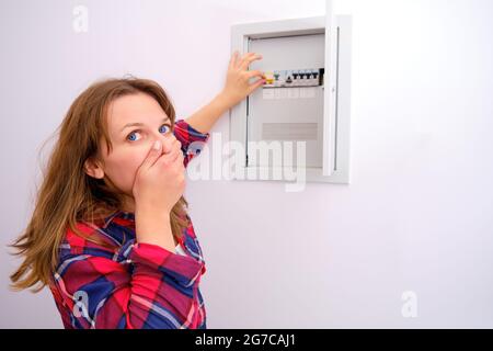 Housewife is afraid to turn on the switch in the shield with electricity in the apartment, copy space Stock Photo