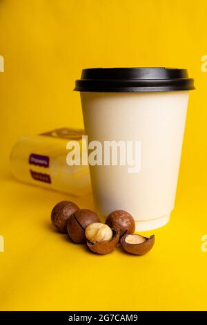 a glass of coffee with macadamia nuts on a yellow background. Stock Photo