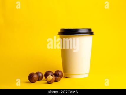 a glass of coffee with macadamia nuts on a yellow background. Stock Photo