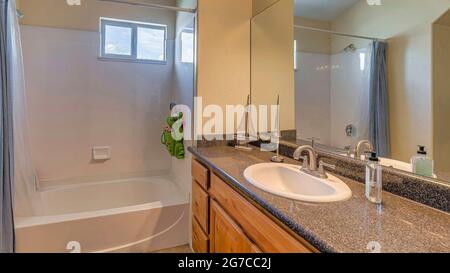 Pano Sink on marble countertop over brown cabinets against mirror and bathroom lights Stock Photo
