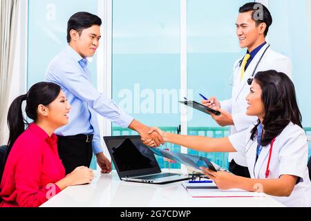 Asian doctor giving patient in office advice with X-ray photograph Stock Photo