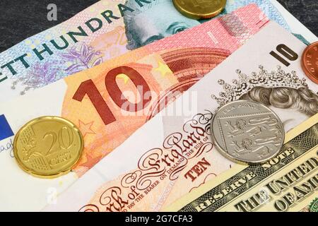 Euro, American Dollar, Swedish Kroner and British Sterling notes and coins on a slate background. Stock Photo