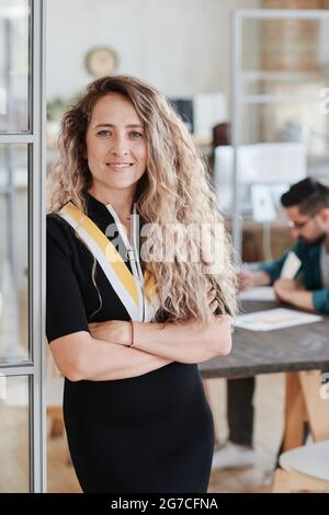 Portrait of young beautiful businesswoman smiling at camera while working at office with her colleagues Stock Photo