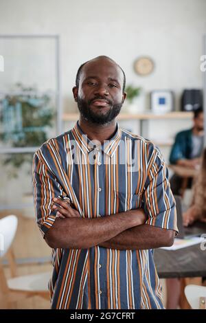 Portrait of African young businessman standing with arms crossed at office and looking at camera Stock Photo