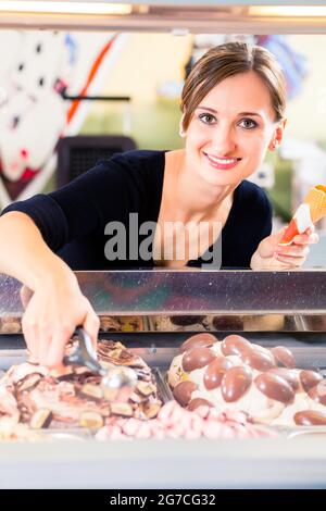 Ice-cream seller portion a scoop of ice cream to wafer in parlor counter or cafe Stock Photo