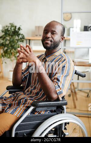 Portrait of African disabled man sitting in wheelchair and looking at camera he working at office Stock Photo
