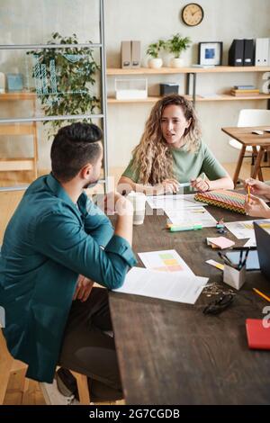 Young business people sitting at the table with documents and discussing financial report in team during meeting at office Stock Photo
