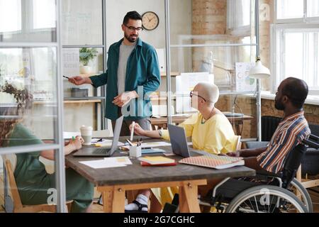 Young businessman holding presentation for his colleagues during a meeting in board room they planning work together Stock Photo