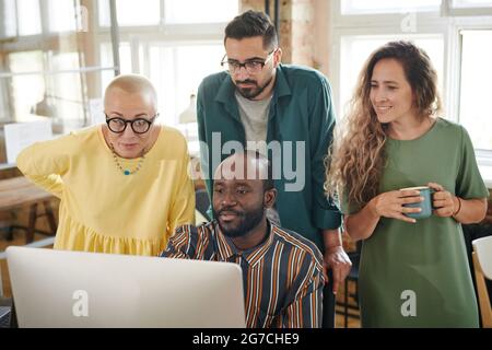 Group of business people watching online presentation together on computer at office Stock Photo