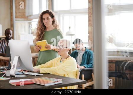 Two businesswomen working over design project together on computer at office Stock Photo
