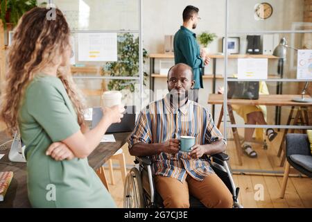 Business colleagues talking to each other and drinking coffee at office during coffee break Stock Photo