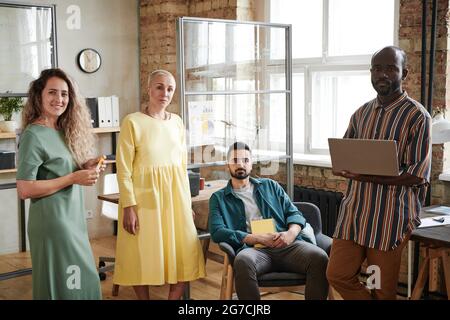 Group of young designers smiling at camera while working in team at office Stock Photo