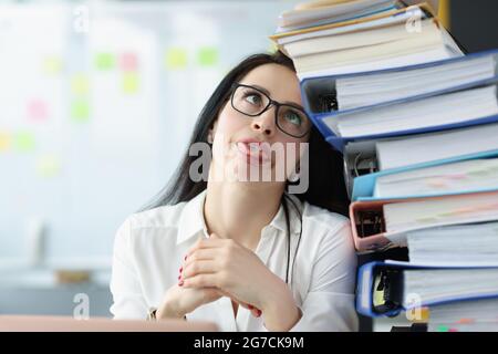Tired young woman sitting at desk with lot of documents closeup Stock Photo