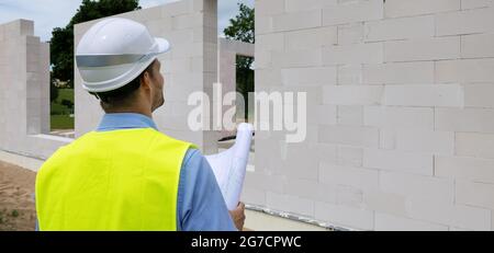 engineer architect with blueprint at residential building construction site. project planning and supervision. banner copy space Stock Photo