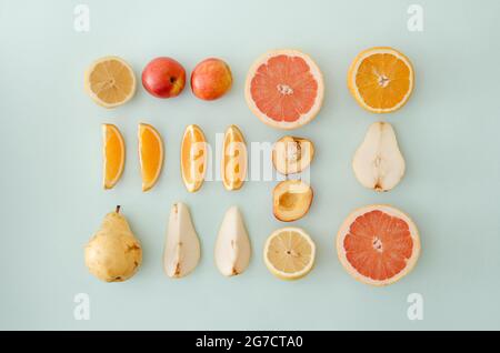 Neatly arranged fresh fruit on blue colored background. Minimal flat lay. Stock Photo