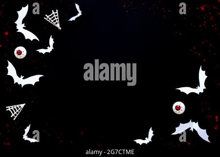 Halloween background made with white paper bats and scary eyes on black background.Copy space template. Stock Photo