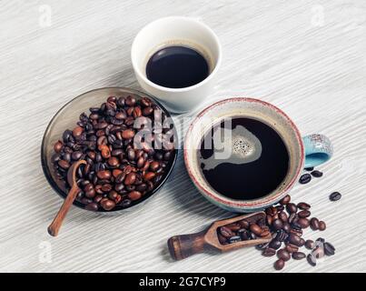 Photo of fresh tasty coffee on light wood table background. Coffee cups and coffee beans. Stock Photo