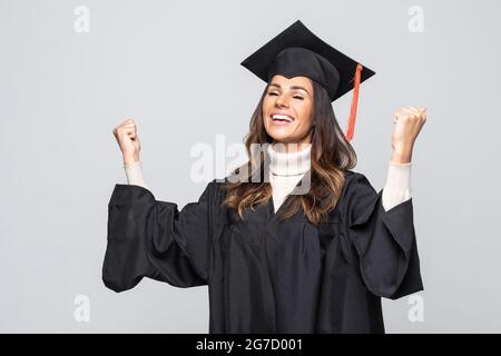 Young woman wearing graduate uniform over isolated background celebrating surprised and amazed for success with arms raised and open eyes. Stock Photo