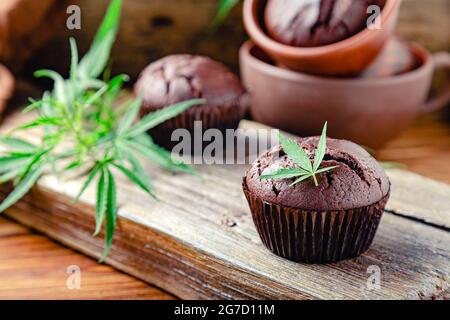Chocolate cupcake muffins with cannabis leaves, weed cbd. Medical marijuana hemp drugs in food dessert. Cooking baking chocolate weed muffins. Cupcake Stock Photo