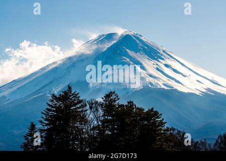 Snow covered icy peak of Mount Fuji. Japan's highest mountain and active volcano. Winds blowing snow from the mountain peak. Stock Photo