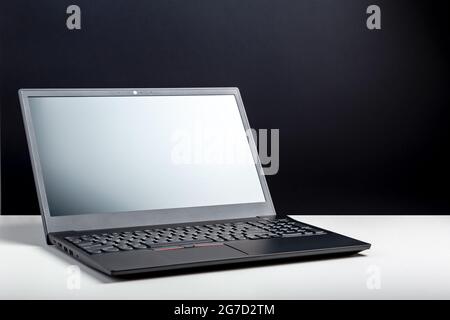 Empty open laptop with mockup on white desk table with black screen. minimalist work space with modern notebook. Personal laptop screen template for Stock Photo