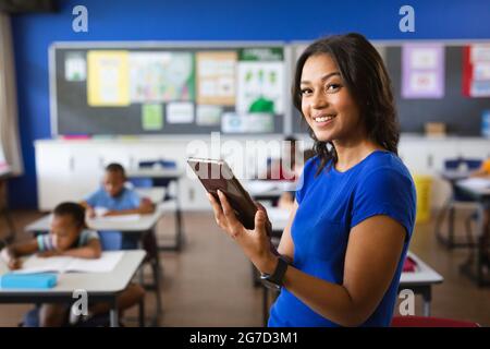 Portrait of african american female teacher holding digital tablet in the class at school Stock Photo
