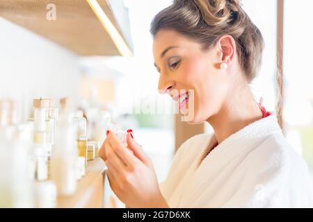 Woman in bath robe choosing face care products in wellness spa Stock Photo