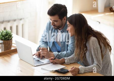 Couple looking at laptop screen analyzing expenses managing family budget Stock Photo