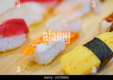 Closeup on Japanese ebi shrimp and tamagoyaki grilled egg sushi with other seafood pieces of rice hand-pressed nigirizushi including ika squid, hotate Stock Photo