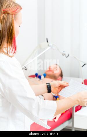 Female doctor analyzing ECG electrocardiogram of patient in hospital Stock Photo