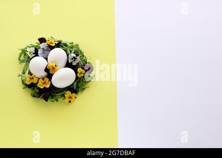 Chicken eggs in a nest made of salad leaves and flowers. Stock Photo