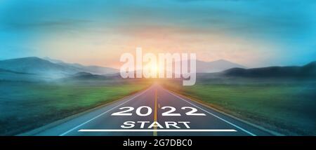 New year 2022 or start straight concept. word 2022 written on the road in the middle of asphalt road at sunset. Concept of planning and challenge, bus