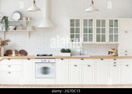 Kitchen interior with whitewashed brick walls, modern furniture, wooden countertop Stock Photo